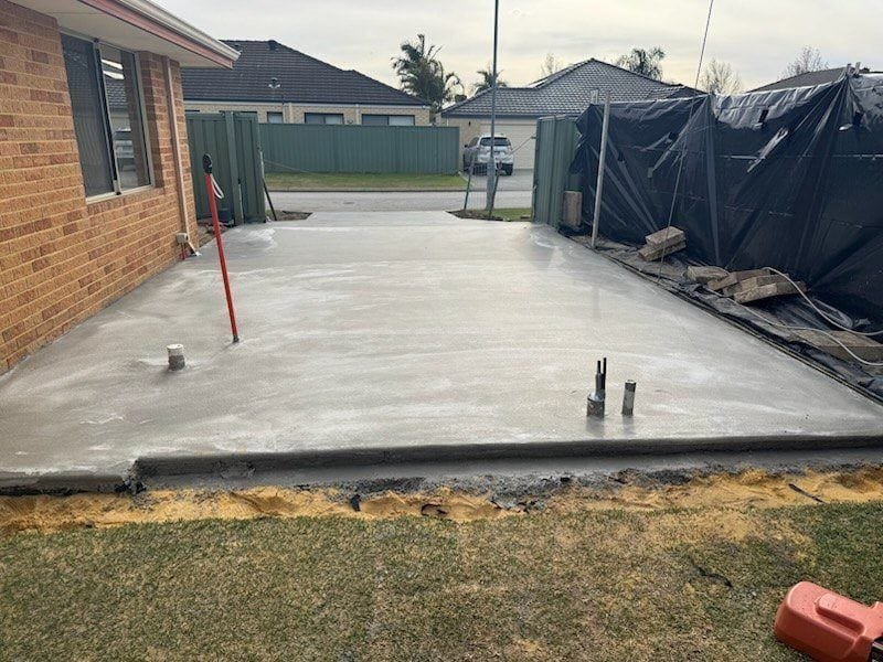 Backyard concrete slab freshly poured behind a brick home