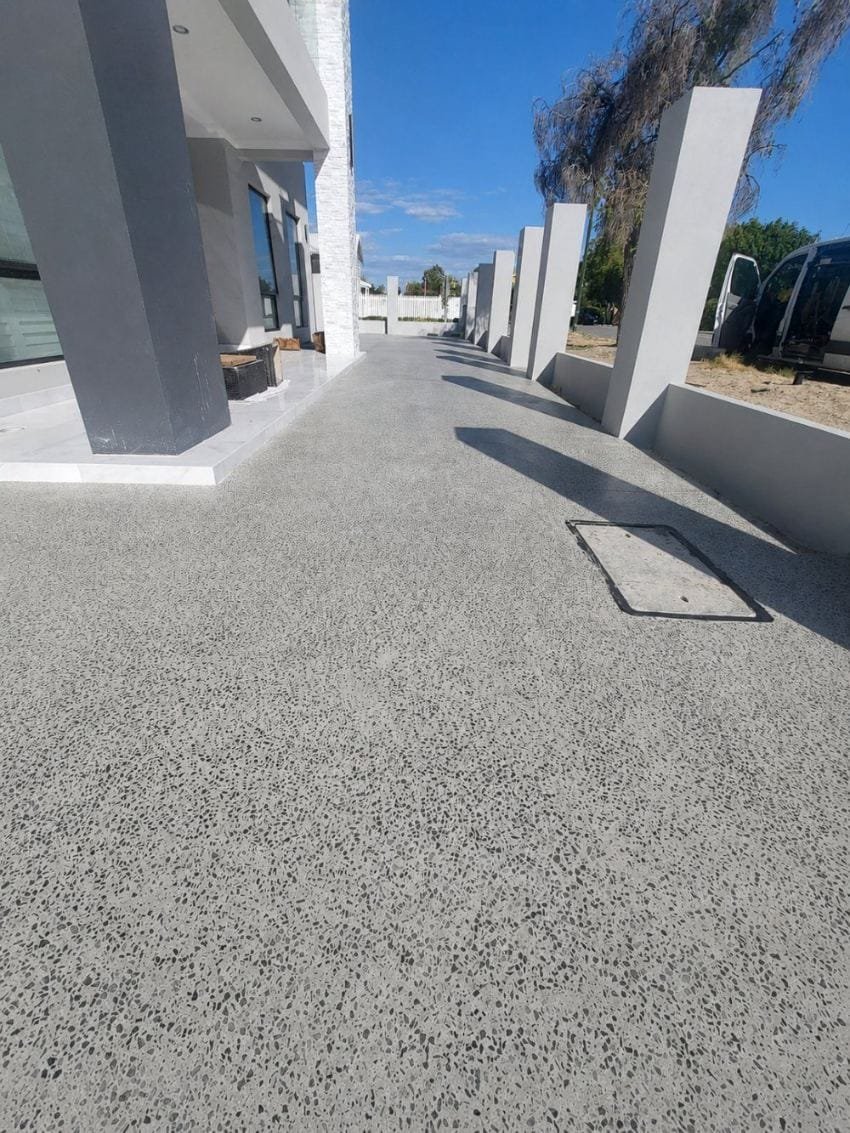 Exposed aggregate courtyard beside a modern home with feature blade walls